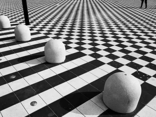 Massi ovali su pavimento a scacchi, un gioco di prospettiva e ombre. #streetphotography