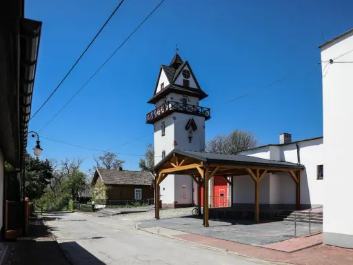 Wieża zegarowa i drewniany domek w słoneczny dzień.