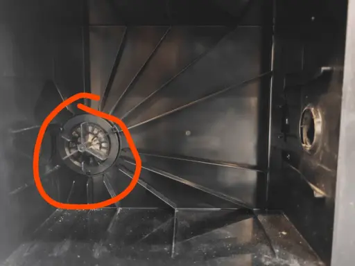 Der Staubbehälter eines Ecovacs Saugroboters, bereit zum Wechseln des Staubbeutels. Der Lüfter ist mit Staub bedeckt.