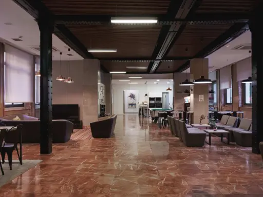 Amplio salón con suelo de mármol rojo, sofás, mesas y una mesa de billar. La **residencia diagonal** ofrece un espacio moderno y acogedor.
