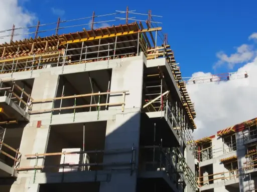 Rohbau eines Mehrfamilienhauses im Rahmen der Entwicklung von urbane gebiete. Gerüste und Betonstrukturen unter blauem Himmel.