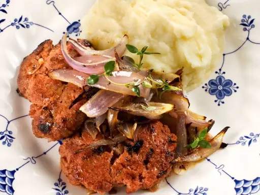 En saftig pannbiff i ugn, toppad med karamelliserad lök och en klick krämigt potatismos. En klassisk svensk rätt som värmer själen.