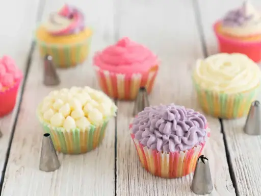 Bunte Muffins verzieren: Rosa, gelbe und lila Frosting-Kreationen mit Spritztüllen.