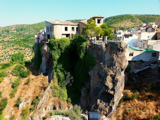 Casas aferradas a un acantilado, con vegetación cubriendo la roca. El mirador de la Molatica ofrece vistas espectaculares del paisaje.