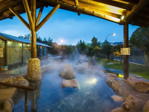Dampfender Thermalpool unter einem Holzpavillon in Ourense, Spanien. Entspannung pur in der Abenddämmerung.