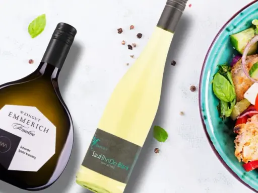 Zwei Flaschen Wein, eine davon eine Scheurebe aus Franken, neben einem bunten Salat.