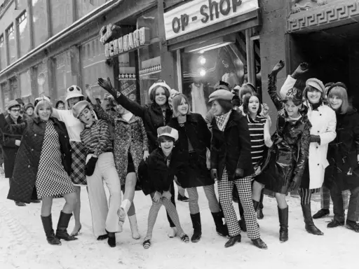 Ungdomar i trendiga kläder utanför en op-shop i Sverige 1960. Snö på marken och glada miner.