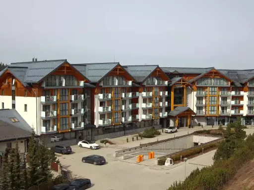 Widok z kamer w Bukowinie Tatrzańskiej na nowoczesny hotel z drewnianymi elementami i parkingiem.