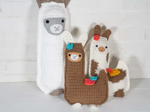 Un grupo de adorables llamas amigurumi, hechas a mano con lana, posan juntas.