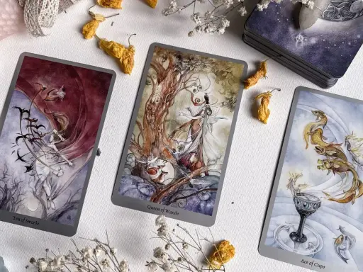 Trzy karty tarota: Dziesiątka Mieczy, Królowa Buław i As Kielichów, tworzą magiczną atmosferę. Idealne do wróżenia, jak tarot online, który się sprawdza.