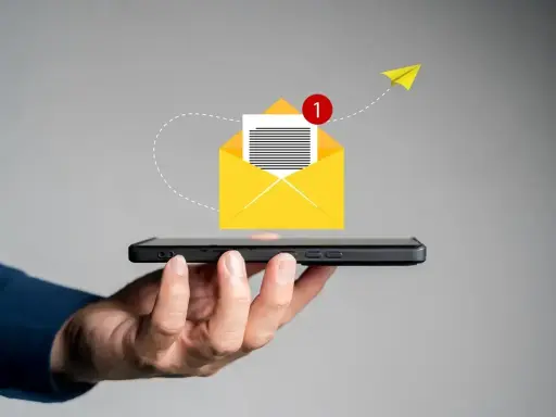 Dłoń trzyma smartfon, z którego wylatuje żółta koperta z powiadomieniem. Jak napisać SMSa o urlop na żądanie?