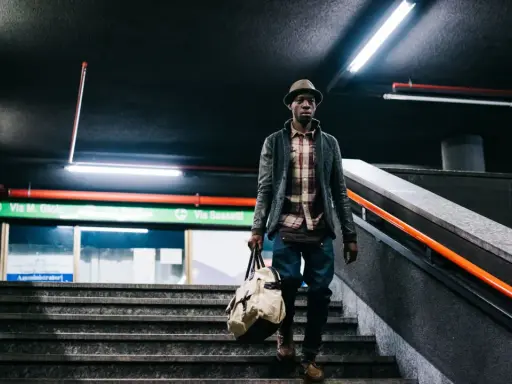 Uomo con borsa scende le scale di una metropolitana, un'immagine con un'atmosfera urbana e moderna. Queste foto creative catturano momenti di vita quotidiana.