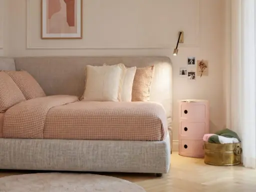 Camera da letto ragazza aesthetic: letto accogliente con biancheria a quadretti, cuscini morbidi, comodino rosa e decorazioni murali.