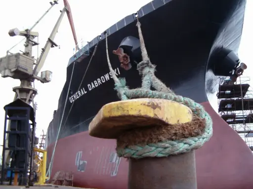 Gros plan sur une aussière, définition de l'amarrage d'un navire, le "GENERAL DABROWSKI", au port. Grues et échafaudages en arrière-plan.