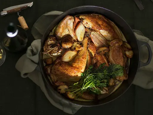 Ein Brathähnchen mit Zwiebeln und Kräutern, bereit zum Genuss. Dazu ein Glas Wein, der den Riesling Geschmack unterstreicht.