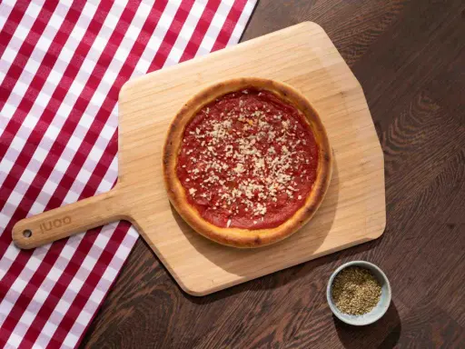 Pizza sur planche en bois, avec une nappe à carreaux rouges et blancs. La proportion levain farine eau est parfaite pour cette croûte dorée.