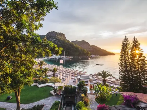 Malownicza zatoka z łodziami, plaża z leżakami i palmami, a na zboczu wzgórza wspaniały hillside beach club.
