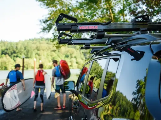 Ludzie przygotowują się do wodnej przygody, transport kajaka i desek SUP do jeziora.