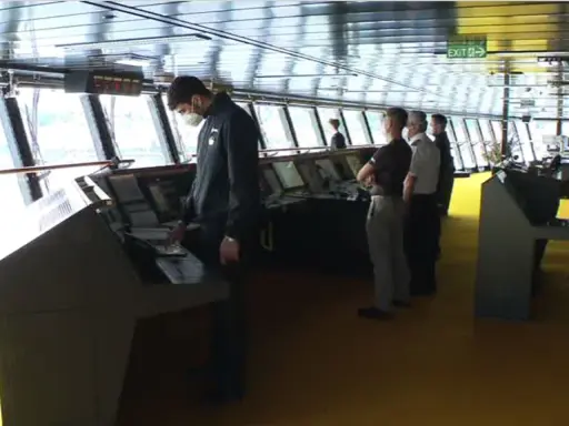 Equipaggio sulla plancia nave da crociera, con strumenti di navigazione e grandi finestre.