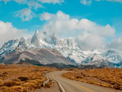 Droga wije się przez trawiastą równinę w kierunku majestatycznych, ośnieżonych szczytów Patagonii. Idealne miejsce dla marki Patagonia.