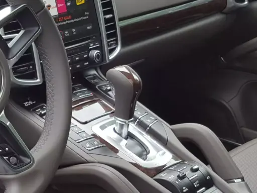 Elegancka skrzynia biegów automatyczna w luksusowym samochodzie. Drewniane wykończenia i chromowane detale podkreślają jej prestiż.