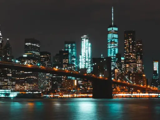 Il Ponte di Brooklyn illumina la **new york city vita notturna**, con grattacieli scintillanti che si riflettono sull'acqua scura.