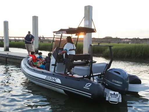 Bateau Zodiac prêt pour l'aventure, son hypalon garantissant une longue durée de vie. Famille à bord, profitant du coucher de soleil.