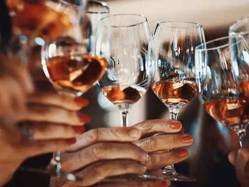Hände halten Gläser mit Roséwein. Ein Genuss ohne Sulfite, vegan und köstlich.