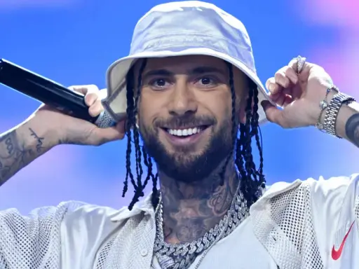 Malik Montana we Wrocławiu, w białym bucket hat, z mikrofonem w dłoni, uśmiecha się do fanów.