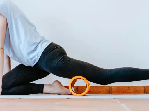 Frau in Sportkleidung dehnt sich mit einem Faszienroller.