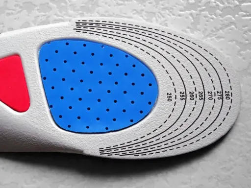 Semelle orthopédique personnalisée, une ordonnance podologue pour un confort optimal. La semelle présente une zone bleue perforée et des repères de taille.