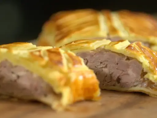 Tranche d'un plat lorrain, une viande savoureuse enveloppée dans une pâte feuilletée dorée.