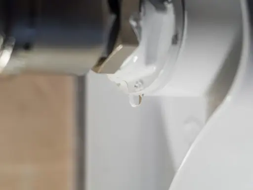 Una gota de agua cae de la rosca de un radiador. El radiador pierde agua por la rosca, indicando una posible fuga.