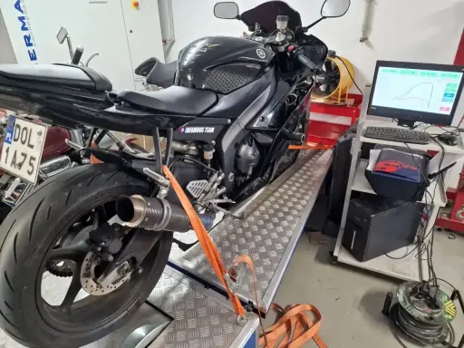 Czarny motocykl na hamowni, przygotowany do **blokowania motocykla na A2**. Pomiar mocy i momentu obrotowego.