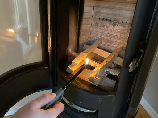 Tända en brasa i kaminen med tändare. Viktigt med brandskydd kamin för säkerhet.