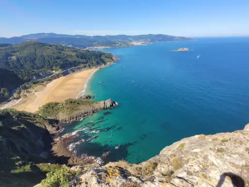 Blick vom Berg auf eine Bucht mit Sandstrand und türkisfarbenem Meer. Perfekt für eine Wanderung im Baskenland.