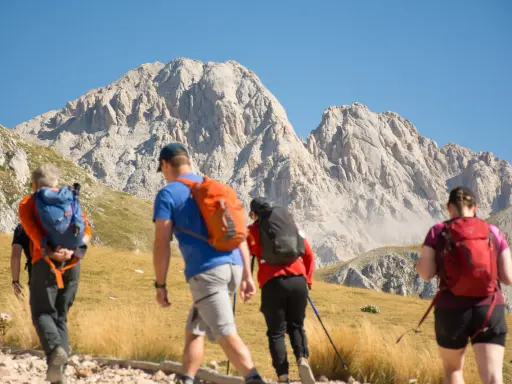 Escursionisti si dirigono verso un imponente corno grande, con zaini colorati e bastoncini da trekking.