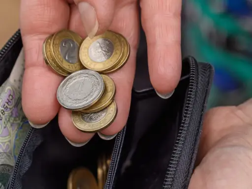 Dłoń z monetami i banknotami w portfelu. Czy to wystarczy na emeryturę po 40 latach pracy? Kalkulator emerytalny pomoże to sprawdzić.