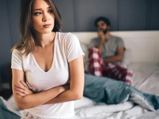 Kobieta zmartwiona, mężczyzna w tle. Problemy intymne, może uczulenie na spermę?