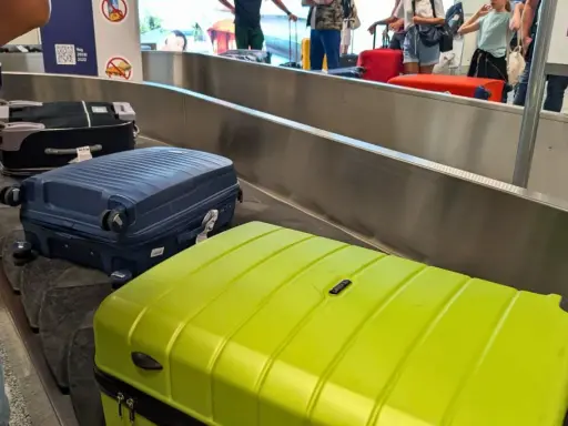 Walizki na taśmie bagażowej. Zastanawiasz się, co zabrać na wakacje all inclusive? Oto inspiracja!