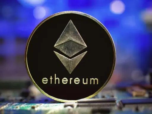 Złoty token Ethereum z symbolem sieci i napisem "ethereum" na tle niebieskiego światła i obwodów drukowanych. To symbol technologii ERC-20.