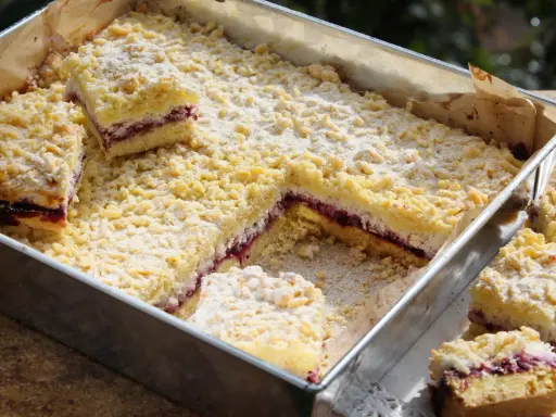 Pyszne ciasto z dżemem porzeczkowym, posypane kruszonką i cukrem pudrem, kroimy na kwadratowe kawałki.