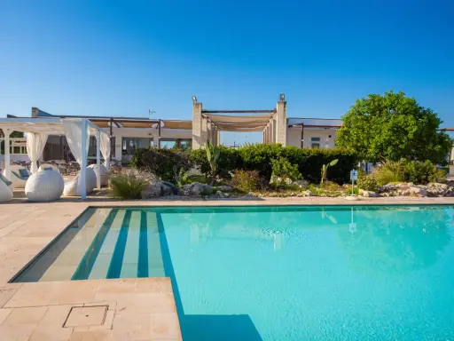 Piscina cristallina e lettini bianchi al le cesine resort, sotto un cielo azzurro. Relax e natura.