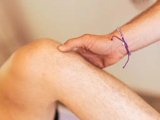Ein Finger tastet das Knie ab, als ob ein Schleimbeutel im Knie geplatzt wäre.