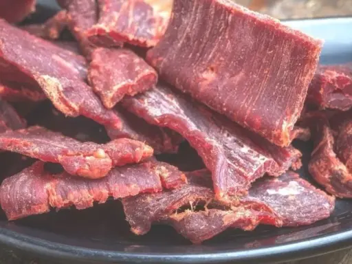 Suszone plastry wołowiny na czarnym talerzu. Idealne do przekąski, gdy szukasz prostego beef jerky przepis.