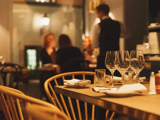 Ett dukat bord med vinglas och servetter, redo för en matvandring i Stockholm. I bakgrunden syns gäster och personal i en mysig restaurangmiljö.