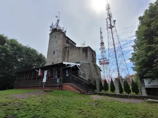 Kamienna wieża i maszty telekomunikacyjne na **chełmiec szczyt**. Drewniana przybudówka z flagami Polski.