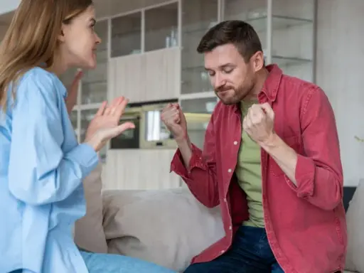 Coppia in conflitto, lei gesticola con rabbia, lui stringe i pugni. Una scena che illustra le difficoltà nel come convivere con un narcisista.