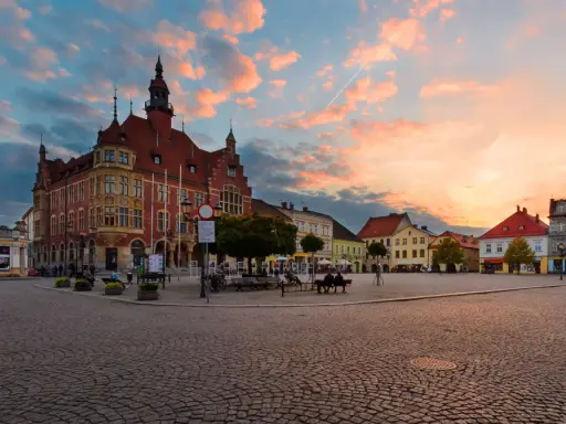 Rynek w Tarnowskich Górach o zachodzie słońca. Kolorowe chmury nad zabytkową zabudową i brukowanym placem, tworzą malownicze tarnowskie góry atrakcje.