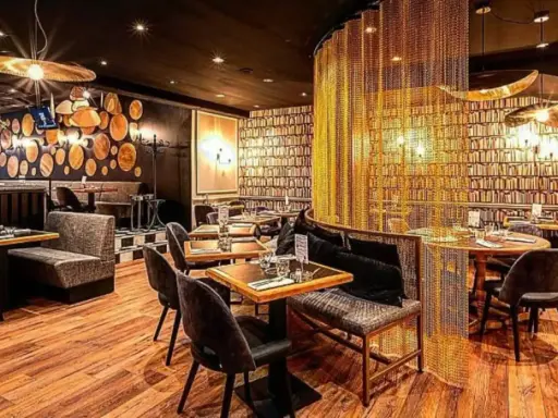 Intérieur chic du restaurant Letz, avec des tables dressées, des banquettes confortables et un rideau de chaînes dorées.